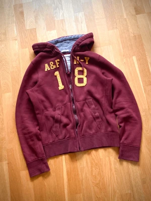 Vintage Aberchrombie & Fitch zip hoodie - Hej! Säljer denna sällsynta A&F zip hoodie som jag inte har sett någon annanstans i en jättefin vinröd färg. På lappen står det L men det passar mycket bättre S/M. Hör av dig ifall du vill ha mått!  Skicka gärna bud!  Sökord: Grisch archive Selvedge selvage y2k hysteric glamour dondup Jacob cohen Maison margiela Levis 501 vintage Levis Vintage style nudie jeans acne our legacy Hollister Abercrombie & fitch number (n)ine yung Lean 