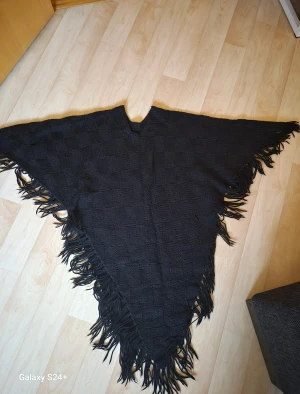 svart stickad poncho med fransar.  - svart stickad poncho med fransar. 