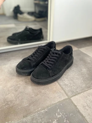Svarta sneakers i mocka från Vagabond - Säljer ett par svarta sneakers från Vagabond i mjuk mocka med platt sula och rund tå. Skorna har klassisk snörning och är riktigt schyssta💥. Storlek 43 och relativt Ny, använt de endast fåtal gånger och lådan finns kvar. Nypris: 1300,