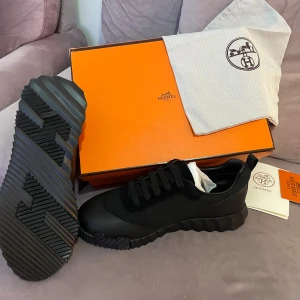 Svarta sneakers  - Snygga svarta sneakers med chunky, räfflad sula och rund tå. Ovandelen är i en mix av textil och skinn, med klassisk snörning. Perfekt för dig som gillar exklusiv design och vill sticka ut med en unik sula. Levereras med originalkartong och dustbag.