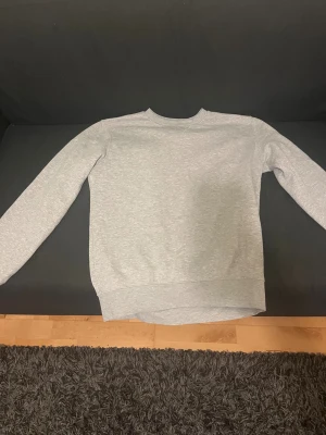 Grå tröja utan huva - En varm, bekväm och stilren tröja. Perfekt till skolan eller en chill dag.