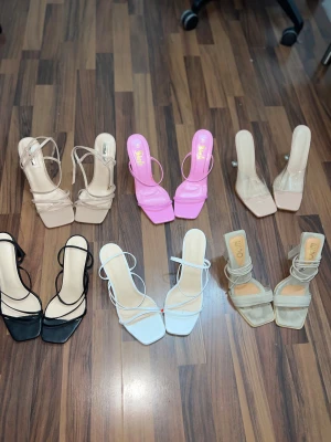 Färgglada sandaler med klack - Säljer flera par trendiga sandaler med klack i olika färger: beige, rosa, svart, vit och grå. Alla har fyrkantig tå, smala remmar och plattforms- eller blockklack. Materialen varierar mellan syntet och mocka. Perfekt för dig som gillar att sticka ut med din stil. Pris från 75