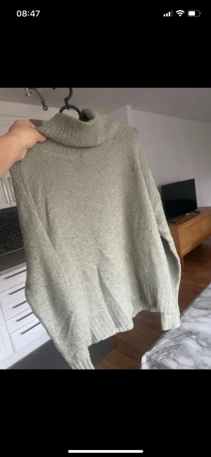 Ljusgrön stickad polotröja - Mysig ljusgrön stickad polotröja med bred polokrage och avslappnad passform. Tröjan har långa ärmar och ribbade muddar vid ärmslut och nederkant. Perfekt för kyliga dagar och enkel att styla till jeans eller kjol.