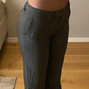 Massimo Dutti lågmidjade kostymbyxor - Massimo Dutti lågmidjade kostymbyxor, grå randiga med låg midja. Lite slitna vid byxkanten men i övrigt fint skick. Svårtolkat storlek men jag skulle säga runt storlek M