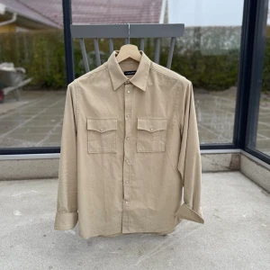 J.Lindeberg Overshirt  - Modell ”Carlos”. Beige färg, kvitto och tag borde finnas, hör av er vid frågor isåfall. Knappt använd, som ny. Extra knapper följder med. I Manchester matrial. Passar bra för längder runt 175-185, vikter 65-80 pannor om jag fick uppskatta. Ganska rak cut (passform). Man kan enkelt ha 1-2 lager under om så önskas. 