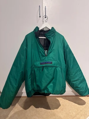Grön och svart Polo Sport jacka - Säljer en fet vändbar jacka från Polo Sport Ralph Lauren. Ena sidan är grön med stor magficka och broderad logga, andra sidan är svart, quiltad och har broderad POLO-text på ryggen. Jackan har half zip och loose fit. Perfekt för dig som vill sticka ut.