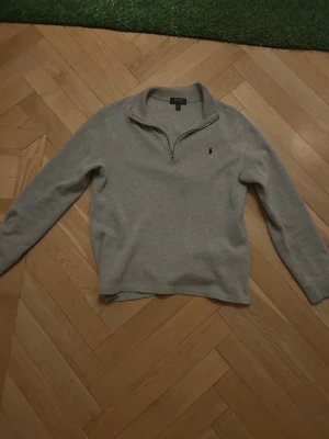 Grå half zip tröja från Polo Ralph Lauren - Snygg grå långärmad tröja från Polo Ralph Lauren med half zip och klassisk broderad logga på bröstet. Tröjan har en mjuk bomullskänsla och passar perfekt för chill dagar. Enkel och stilren design som funkar till jeans eller mjukis. Jättefint skick förutom en liten fläck på magen. säljer för att jag  har växt ur den, jätte skönt material till vintern.