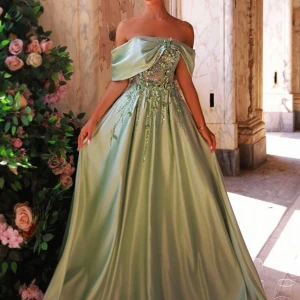 Mintgrön offshoulder balklänning - Drömmig mintgrön långklänning i satin med offshoulder och stor rosett i ryggen. Klänningen har vackra broderade detaljer och pärlor över livet samt en svepande kjol som ger en riktigt sagolik känsla.