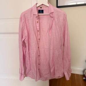 Ljusrosa linneskjorta från Salmapolo - Säljer en ljusrosa skjorta från Salmapolo i luftig linnemix. Skjortan har klassisk krage, knappar framtill och broderad logga på bröstet. Perfekt för dig som gillar en chill och stilren look. Stryker vid begäran. 