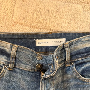 LOWWAIST Blå bootcut jeans från Bershka - LOWWAIST Snygga blå jeans från Bershka i bootcut-modell med klassisk femficksdesign och dragkedja. Jeansen har en lätt tvättad look och är tillverkade i jeansmaterial med normal passform. Perfekta för dig som gillar retrovibbar och vill ha ett coolt statement. Tveka inte på att höra av dig vid frågor eller intresse!