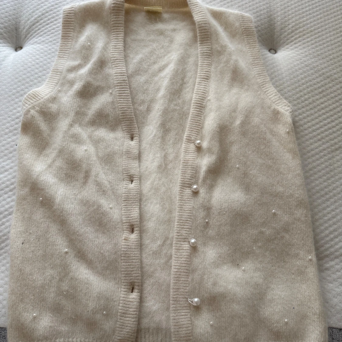 Vit stickad väst med pärldetaljer