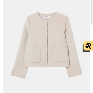 Beige croppad kavajjacka med fickor - Stilren höst jacka i beige med två fickor framtill. Jackan har lång ärm och minimalistisk design som ger en clean look. Perfekt för dig som gillar en modern och enkel stil. Köpt för 2000