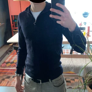 Halfzip från A Day's March - Säljer en marinblå långärmad tröja från A Day's March i mjuk merinoull. Tröjan har en clean half zip-dragkedja och hög krage, perfekt för lager-på-lager. Snygg och enkel att matcha till olika outfits. Tröjan är i fantastiskt skick. Fråga vid minsta fundering😊