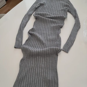 Grå ribbad långklänning Even&Odd - Säljer en långärmad, ribbad långklänning från Even&Odd i mellangrå nyans. Klänningen är figurnära och har ett stilrent randigt mönster. Materialet består av 81% viskos och 19% polyamid vilket gör den mjuk och stretchig. Perfekt för dig som gillar minimalistisk och clean stil.