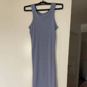 Ljusblå ribbad klänning från 157 - Supersnygg ljusblå ribbad klänning från 157 i figurnära modell. Ärmlös med breda axelband och rund halsringning. Tillverkad i 100% bomull, perfekt för en chill och stilren look. Storlek Xs men passar mig som är S 