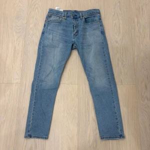 Levi's 512 ljusblå jeans - Ljusblå Levi's 512 jeans med klassisk femficksdesign och smal passform. Jeansen har en snygg tvättad look, raka ben. Perfekta för dig som gillar en clean och tidlös stil. W32 L30