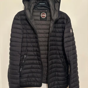Svart pufferjacka från Colmar - Säljer en svart pufferjacka från Colmar med huva och dragkedja. 