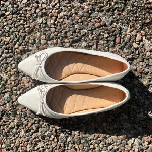 Vita ballerinaskor från Anna Field - Snygga vita ballerinaskor från Anna Field med spetsig tå och dekorativ rosett framtill. Skorna har quiltad innersula för extra komfort och en platt sula. Perfekta för dig som gillar en stilren och klassisk look.