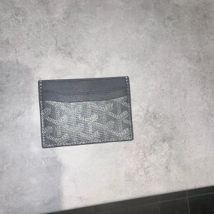 Svart kortfodral från G yard - Snyggt svart kortfodral från Gyard med ikoniskt mönster i vitt och grått. Fodralet har flera kortfack och är gjort i exklusivt skinn med Gyqed klassiska tryck. Perfekt för dig som vill ha en stilren och lyxig accessoar i fickan.