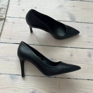 Svarta klassiska klackskor - Svarta pumps med spetsig tå och hög klack. Endast använda vid 1 tillfälle. Sköna att gå i. Säljer endast då de är för stora