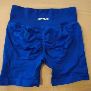 Blå träningstights shorts från DFYNE - Säljer ett par blå träningstights shorts från DFYNE med hög midja och scrunch-detalj bak. Perfekta för gymmet eller löpning, sitter tight och bekvämt. Materialet är stretchigt och andas bra.