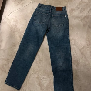 Woodbird ljusblå raka jeans 28/32 - Snygga ljusblå jeans från Woodbird i klassisk rak modell. Jeansen har fem fickor, läderpatch med logga bak och normal passform. Tillverkade i bomull och perfekta för en avslappnad stil.