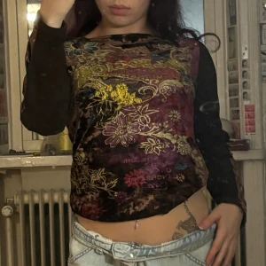 Blommig sammetstopp med lång ärm - Unik topp i mörk sammet med blommigt mönster i gult, blått och rött. Thriftad i vietnam och passar stl xs-s. har print där bak också