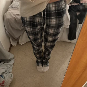 Svarta och vita rutiga pyjamasbyxor - Mysiga pyjamasbyxor i svartvitt rutigt mönster med dragsko i midjan. Byxorna har en loose passform och är perfekta för chill dagar hemma. Tillverkade i mjukt material som känns skönt mot huden.
