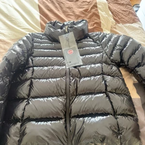 Svart glansig dunjacka från Colmar - Snygg svart dunjacka från Colmar med glansig finish och klassisk quiltad design. Jackan har hög krage, dragkedja framtill och tydlig Colmar-logga på bröstet. Perfekt för kalla dagar och ger en clean streetstyle-vibe., ÄKTA, köptes för 5999, säljs för 4500 men pris kan diskuteras  använt 0 gånger 