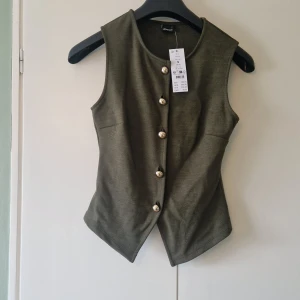 Olivgrön väst med pärlknappar - Stilren olivgrön väst med guld knappar från Gina Tricot. Ny med prislappen kvar. Erbjuder bundel rabatt vid köp av flera varor 🌸