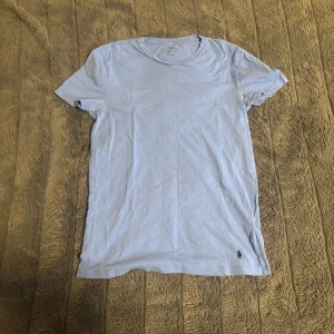 Ljusblå t-shirt från Polo Ralph Lauren - Ljusblå t-shirt från Polo Ralph Lauren i klassisk modell med rund hals och korta ärmar. Tillverkad i mjuk bomull och har den ikoniska lilla broderade loggan nertill. 