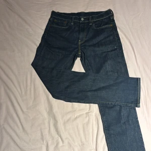 Levi's 522 jeans mörkblå W29 L32 - Mörkblå Levi's 522 jeans med klassisk femficksdesign och kontrastsömmar. Modellen har rak passform och normal midja, tillverkad i slitstarkt denim med läderpatch bak och röd Levi's-tag på bakfickan. Perfekt för dig som gillar tidlös stil.