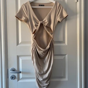 Beige klänning  - Säljer en trendig ärmlös klänning från SHEIN i färgen tan. Klänningen har en snygg knytning fram och en cut-out detalj vid magen. Perfekt för olika tillfällen! Använd endast 1 gång och är storlek M.  Vänligen läs min bio innan du gör ett köp; där hittar du bland annat information om leveransprocessen med mera 😊  #SHEIN #klänning #trendig #mode #fashionista