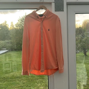 Orange skjorta från Ralph Lauren - Säljer en snygg orange långärmad skjorta från Ralph Lauren med klassisk button-down krage och broderad logga på bröstet. Sjukt stilren och bra skick. Säljer för att jag växt ur den.  Använt 3 gånger 