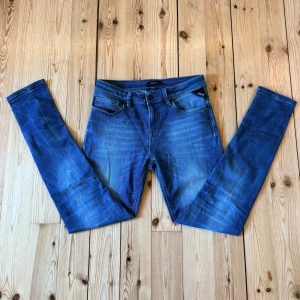 Blå skinny jeans från Replay - Snygga blå jeans från Replay med klassisk femficksmodell och tydliga slitningar framtill. Jeansen har smal passform och normal midja, tillverkade i stretchigt denim för extra komfort. Perfekta för dig som gillar en modern och stilren look.