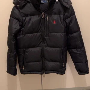 Svart pufferjacka från Polo Ralph Lauren - Säljer min Ralph Lauren jacka eftersom den inte längre passar mig, köpte förra året storlek S men har nu växt lite och behöver ny jacka inför vintern. Försöker få jackan såld snabbt och säljer därför mkt billigare