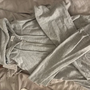 Grå hoodie från Even&Odd med dragkedja - Säljer en ljusgrå hoodie från Even&Odd med hel dragkedja framtill och snörning i huvan. Tröjan har långa ärmar och är tillverkad i mjuk bomullsblandning, perfekt för chill dagar eller när du vill vara extra bekväm.