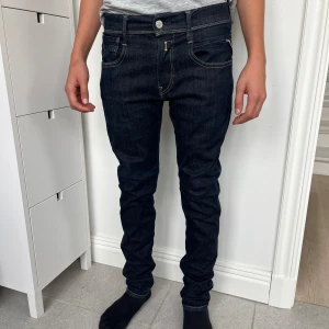 Replay Anbass Hyperflex Jeans, W28 L30 - Säljer ett par mörkblå Replay Anbass Hyperflex slim fit jeans, i jättefint skick. Klassisk femficksdesign och snygga kontrastsömmar. Jeansen är tillverkade i stretchigt jeansmaterial som sitter tajt men bekvämt. Personen på bilden är 161 lång.  Storlek W28 L30