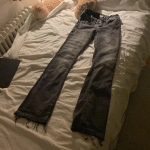 Grå bootcut jeans från Gina Tricot - Säljer ett par grå jeans från Gina Tricot i storlek 158. Jeansen har bootcut-modell med råa, fransiga benslut och klassisk femficksdesign. Materialet är ganska stretchigt och de har dragkedja och dubbla knappar framtill. Tycker själv att det ör väldigt snyggt längst nere, men nu är tyvärr dessa jeansen för små….💕