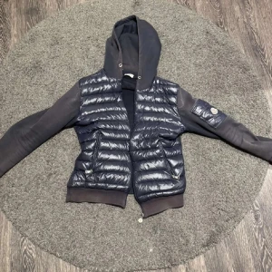 Blå Moncler pufferjacka med huva - Hej säljer en Moncler cardigan för bra pris för att jag behöver pengar, har haft den sen förra året och köpte för 5000kr den har blivit lite solblekt och högra fickan går inte o zippa men de går säkert att fixa 