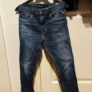 Mörkblå jeans från Replay, 14A - Snygga mörkblå jeans från Replay med klassisk femficksdesign och gul kontrastsöm. Jeansen har raka ben och subtila slitningar framtill för en cool look. Passar dig som gillar stilrena och tidlösa jeans med en modern touch.