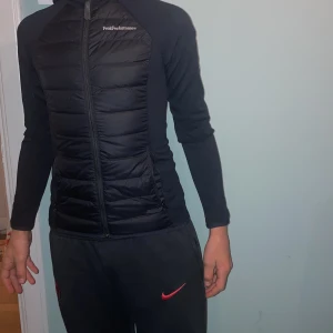 Svart pufferjacka Peak Performance - Peak performance cardigan jacka. Modellen är 164 cm 55kg och sitter tajt på henne. Ingen defekt förutom en fläck på insidan av jackan, se bild 5. Kontakta jättegärna vid frågor och funderingar. Jag kan lösa fler bilder på jackan. Köp gärna nu när det är fri frakt. Den är svart men ser mörkblå ut på bilderna.