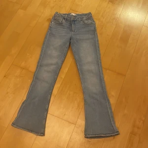 Bootcut jeans från Gina Tricot ljusblå - Ljusblå bootcut jeans från Gina Tricot i storlek 152. Jeansen har klassisk femficksdesign, normal passform och lätt utsvängda ben. Tillverkade i mjukt denimtyg med rå kant nertill för en trendig look. Dem är även upplagda i benen.