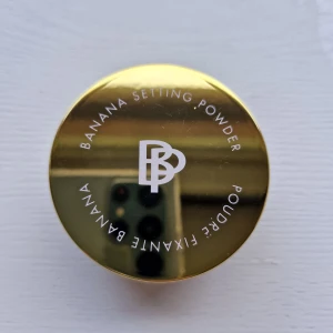 Bellapierre Banana Setting Powder - Banana Setting Powder från Bellapierre i nyansen Original (Light). Löst puder med gul ton som jämnar ut hudtonen och fixerar sminket. Kommer i en rund burk med guldig lock och transparent underdel. Perfekt för att ljusa upp och matta ner huden. Nypris 250kr 