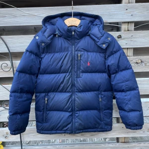 Ralph Lauren Marinblå Dunjacka  - Riktigt stilig dunjacka från Ralph Lauren. Barnstorlek L, motsvarar 160 cl. Fint skick, lite smuts på vissa ställen men i övrigt felfri. Använd en vinter. 