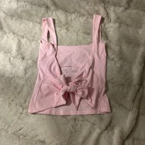 Ljusrosa linnetopp med rosett - Supersöt ljusrosa linnetopp från bikbok med breda axelband och en stor rosett baktill. 