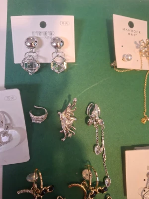 Mix av örhängen clips i silver och guld - Säljer ett gäng trendiga örhängen i olika former och färger. Här finns silverfärgade örhängen med kuber, hjärtan i pärlemor, guldiga hoops med svarta stenar, pärlörhängen och örhängen med glittriga detaljer. Perfekt för dig som vill mixa och matcha olika stilar.