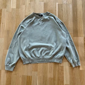 Ljusgrå loose fit sweatshirt H&M - En stilren ljusgrå sweatshirt från H&M i loose fit-modell. Tröjan har rund hals, ribbade muddar vid ärmslut och nederkant samt är tillverkad i en mjuk blandning av bomull och polyester. Perfekt för en chill och avslappnad look.