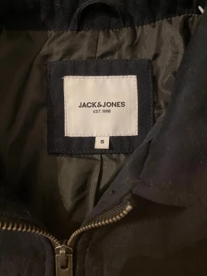 Mörkblå overshirt från Jack & Jones - Stilren mörkblå overshirt från Jack & Jones med klassisk krage, två stora bröstfickor och dragkedja framtill. Riktigt fet! Storleken är i S