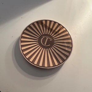 Charlotte Tilbury bronzer medium - Säljer en Charlotte Tilbury bronzer i färgen medium. Kommer i en lyxig rund dosa med roséguldigt mönster och spegel inuti. Perfekt för att ge ansiktet en varm och solkysst look. Pudret är matt och har en mjuk konsistens som är lätt att blenda.